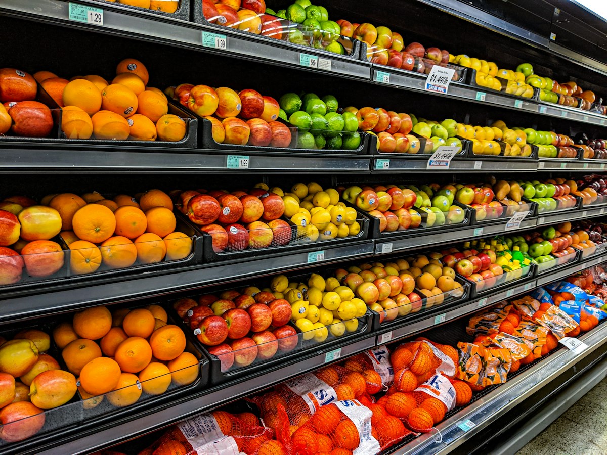 Seções de hortifrúti e produtos frescos com etiquetagem clara de preços nos supermercados internacionais